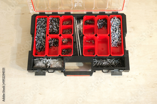 organizer with fasteners on a plywood table. Picture of empty plastic organizer for screws