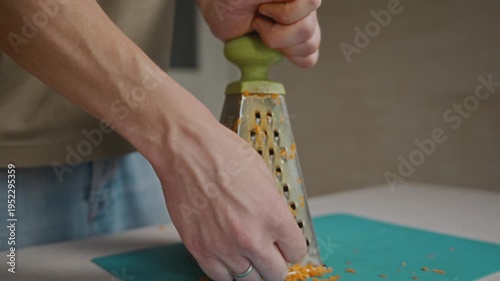 Wallpaper Mural Medium close-up of a man grating carrot with one hand on a kitchen grater. Simple food preparation, vegetable processing and everyday home cooking routine without showing face. High quality 4k footage Torontodigital.ca