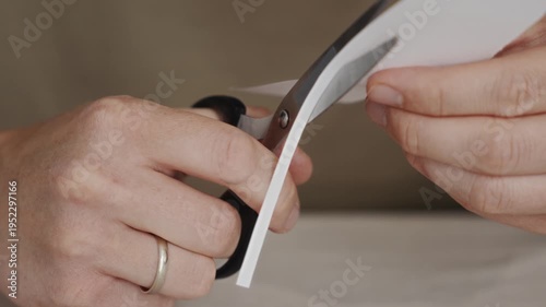 Wallpaper Mural Close-up shot of scissors cutting a sheet of white paper held in hands. Precise manual motion demonstrating everyday cutting process commonly used in craft making or office tasks. High quality 4k Torontodigital.ca