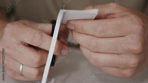 Wallpaper Mural Close-up of scissors cutting a narrow strip from a white sheet of paper. Hands guide the blades carefully as the thin strip bends while separating from the paper. High quality 4k footage Torontodigital.ca