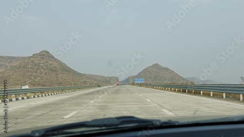 Blue highway safety sign showing keep headway 200 meters on a modern road with guardrails and hills in the background under a clear sky.