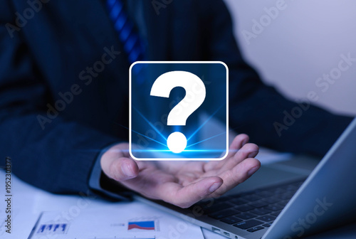 Cuadro en lienzo Businessman holding glowing question mark icon over laptop, symbolizing problem solving, support, FAQ, customer service, uncertainty, decision making and digital technology concept in modern office