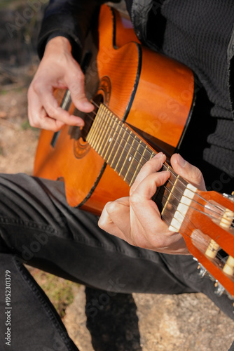 Close up hands of playing string guitar outdoors in autumn forest. Concept of sound therapy, mental health and wellness rituals. Calmness tranquility audio-sensory practices. Aura farming energy