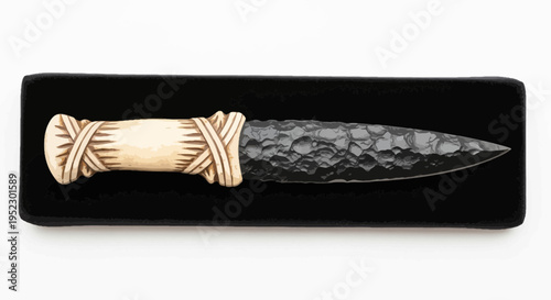 An ancient-style dagger with an ornamented handle resting on a black surface