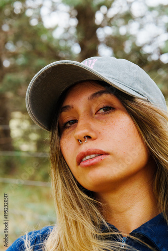 portrait of a young Latino brunette girl using Jeans and a blue shirt in a country setting with a lot of green and trees in the background