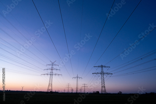 Foto Power pylons at late dawn in a wide, quiet landscape, power line or high-voltage
