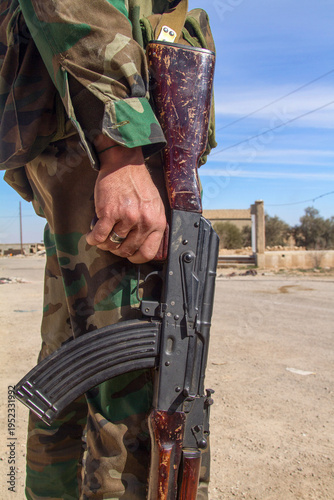 Bild auf Leinwand Syrian Soldier Holding Rifle in War-Damaged Urban Area