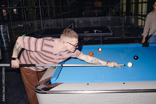 Cuadro en lienzo Caucasian young adult man with short hair and tattoos playing billiards, leaning