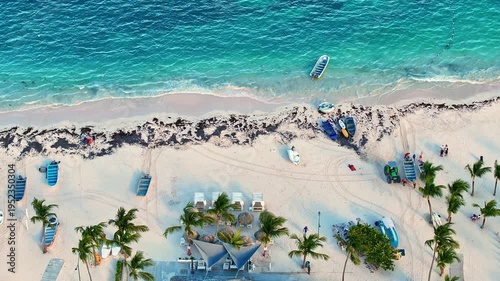 Aerial view of a tropical resort beach with white sand on the sea coast. Boats in the Caribbean Sea on turquoise waves. Summer vacation. Clear waves on the sand. Summer tropical evening.