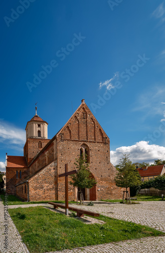 Holzkreuz und Sitzbalken vor der Westfassade der denkmalgeschützten katholische Stadtkirche 
