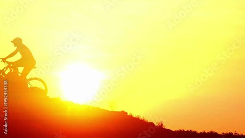 Silhouette of a cyclist riding uphill during a vibrant sunrise