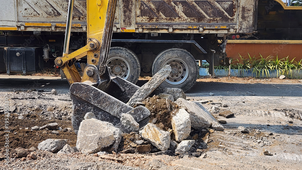Fototapeta premium Excavator Digging Up Road Surface, Excavator loading broken concrete and soil into a dump truck at a construction site, road demolition and site preparation work