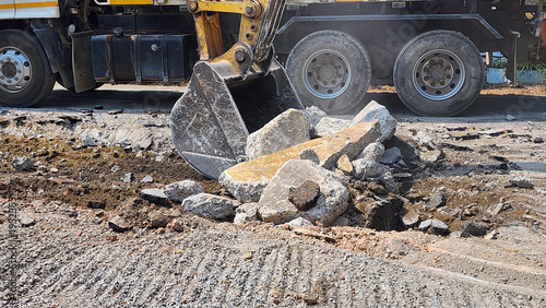 Excavator Digging Up Road Surface, Excavator loading broken concrete and soil into a dump truck at a construction site, road demolition and site preparation work