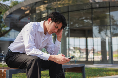 Young businessman feeling stressed getting bad news on smartphone