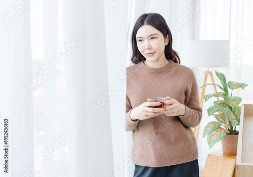 Asian attractive woman standing looking out window holding drinking coffee or tea cup in morning time, sun rise outside peaceful daily life happy enjoy fresh natural light relaxing lifestyle wellness. Free Download Asian attractive woman standing looking out window holding drinking coffee or tea cup in morning time, sun rise outside peaceful daily life happy enjoy fresh natural light relaxing lifestyle wellness. - GFXLoad