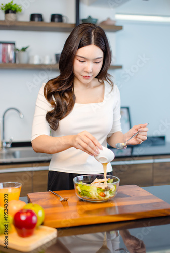 Asian young pretty positive woman standing in kitchen prepare making eating healthy salad from glass bowl cooking healthy food fresh vegetables fruits clean feel good morning happy relaxing lifestyle.