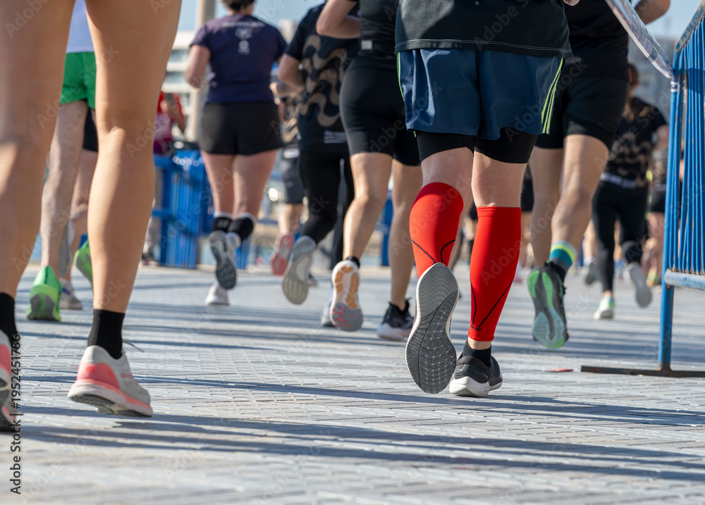 Fototapeta premium Close low angle view of marathon runners legs and shoes on waterfront race course