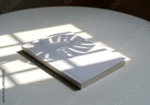 Elegant slim soft cover book mockup with natural window light and plant shadow