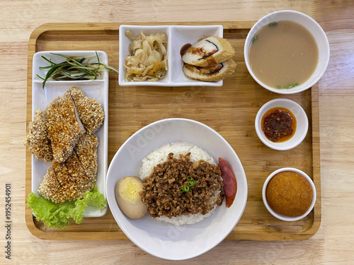 Taiwanese style set meal with rice, soup, side dishes and traditional street food on wooden table.