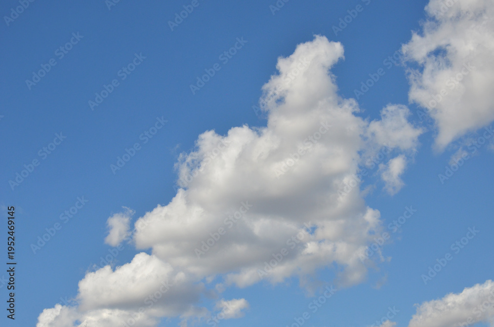 Fototapeta premium White fluffy cloud in the middle of deep blue sky. Nature, beautiful weather, sky in sunny day.