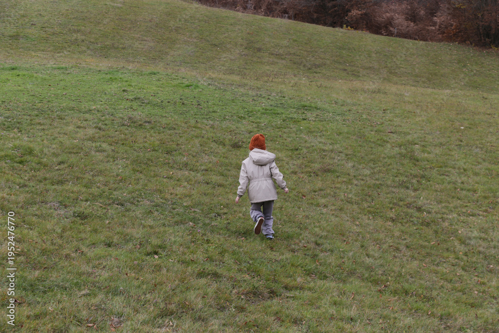 Fototapeta premium Little Girl Walking Over Green Hill Childhood Exploration, Outdoor Adventure, Nature, Discovery and Healthy Lifestyle