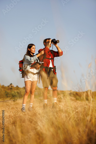 Couple of environmental scientists doing field research in nature watchin and listing birds