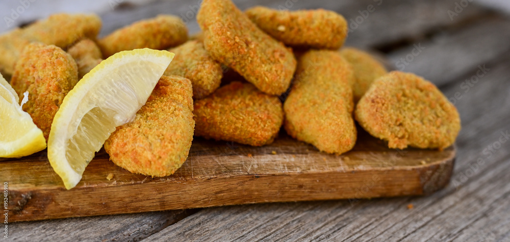 Fototapeta premium Crispy oven baked chicken nuggets and ketchup. Breaded chicken fillets with chilly peppers and fresh basi on wooden rustic background