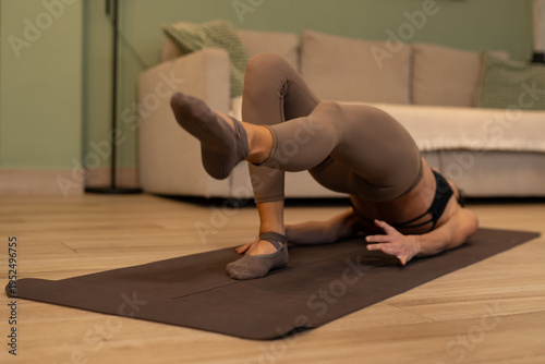 Athletic woman performing pilates bridge leg lift exercise focusing on glute activation core stability strength balance and controlled movement during intense home workout session