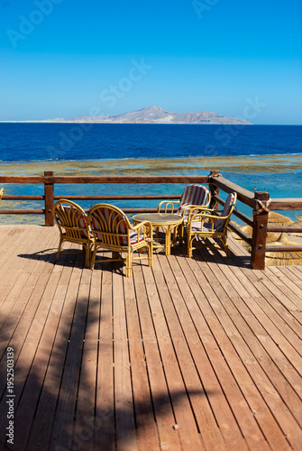 Armchairs and a table stand on the embankment overlooking the sea