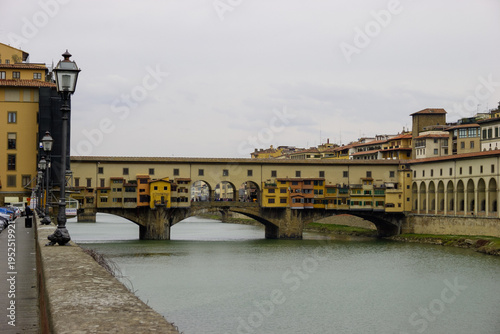 Ponte Vecchio bridge over the Arno River in Florence, Italy, with shops and buildings lining the bridge.