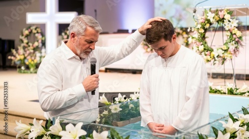 Pastor blessing young man during baptismal ceremony in church. Religious rite of immersion in water for Christian faith. Easter Sunday worship service scene with white flower decoration.
