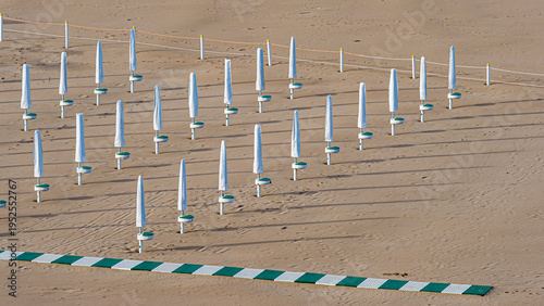 фотографія Closed beach umbrellas casting shadows on sandy Termoli beach