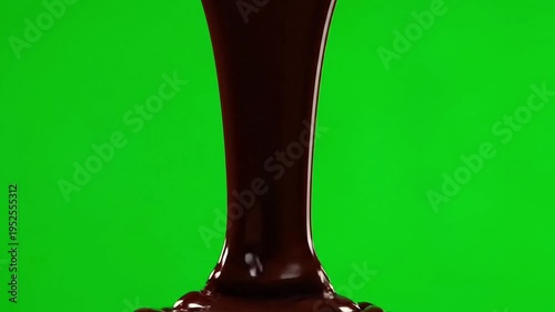 Luxurious melted dark chocolate pouring slowly in a thick, glossy stream against a vibrant green screen