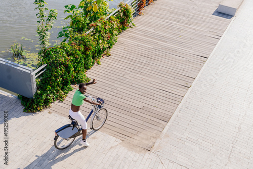 Foto Overhead sporty female waving from rental bike on riverside route