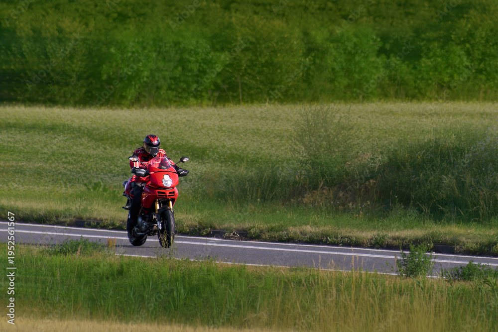 Obraz premium Motorcycle rider moving along a scenic rural road path