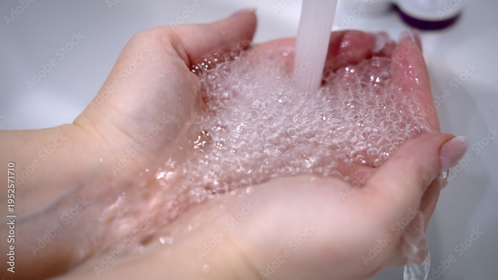 Fototapeta premium water pours through hands at home, water in the bathroom from the tap is pouring through the hands, have fun and enjoy