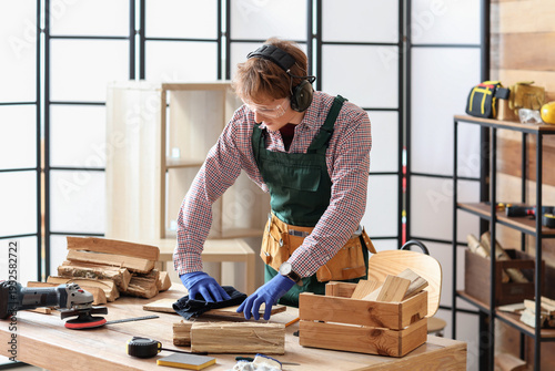 Young carpenter wiping wood...