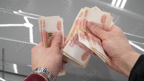 A close-up of a man's hands counts a bundle of bills for five thousand Russian rubles. Man counts red paper 5000 rubles bills. Russian cash money in male hand. A man holds a wad of money in his hands.