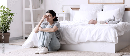 фотографія Stressed mother suffering from postnatal depression with her baby in bedroom