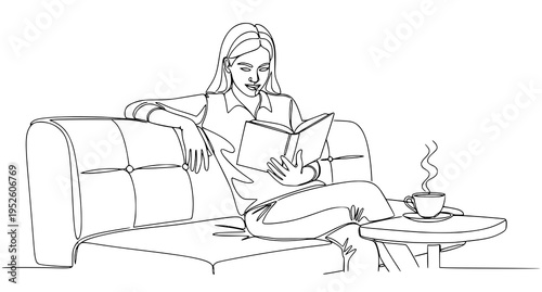 A woman relaxes on a couch reading a book with a cup of coffee
