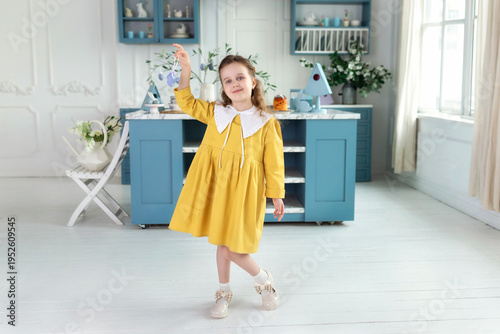Wallpaper Mural Happy Little girl in yellow dress with collar holding Easter colorful eggs in hand in festive kitchen. Cute fun child Girl hunts easter eggs at home. Holiday, spring and family celebration concept. Torontodigital.ca