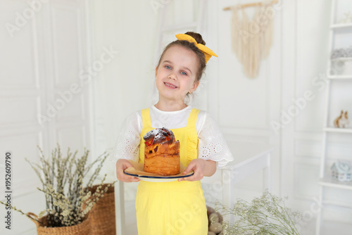 Wallpaper Mural Cute girl in yellow overalls with easter cake in hands. Smile child holding easter pie, celebrating easter and spring. Happy little girl holding a baking with baked cake in her hands on rustic kitchen Torontodigital.ca