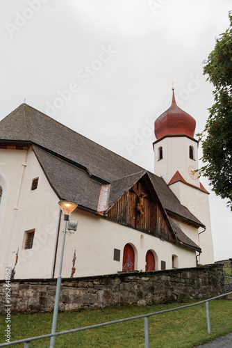 Quadro em tela Historic alpine church with traditional architecture and red onion dome in a quiet Austrian village