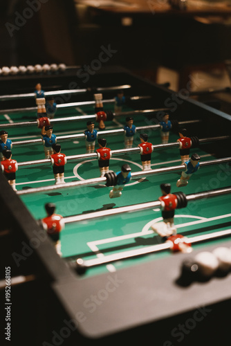 Foosball table with red and blue players in indoor setting, popular game in bars and homes