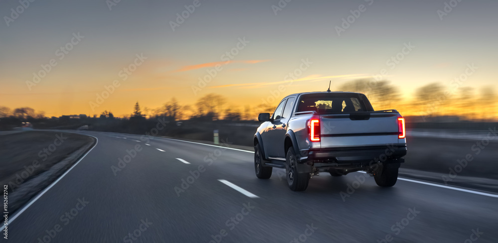 Fototapeta premium Pickup truck driving on open highway at sunset with motion blur. Pickup road travel.