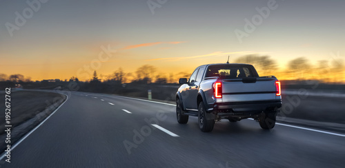 Pickup truck driving on open highway at sunset with motion blur. Pickup road travel.