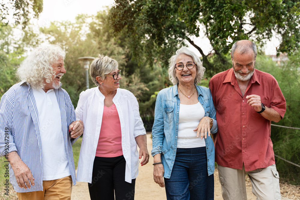 Obraz premium Happy senior friends walking together in park enjoying retirement lifestyle and friendship
