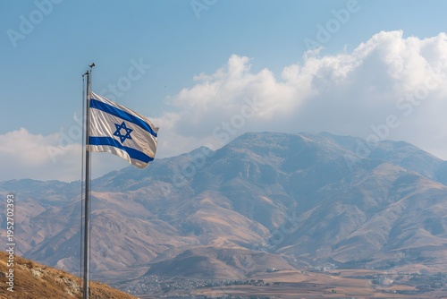 The Israeli flag waves proudly against a backdrop of rugged mountains and a cloudy sky