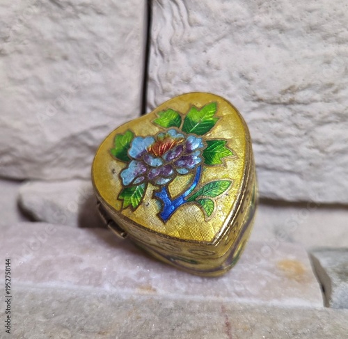 Photography A small heart‑shaped box with a beautifully detailed enamel floral design
