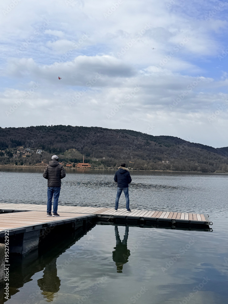 Fototapeta premium Vergiate, Italy - March 18, 2026: Collection of remote controlled seaplanes arranged on a lakeside dock, ready for flight. Detailed scale models used for hobby aviation and outdoor recreation.